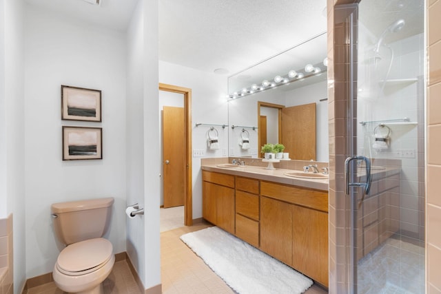full bathroom with double vanity, a sink, toilet, and a shower stall