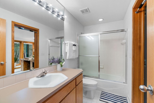 bathroom with vanity, tile patterned flooring, toilet, and shower / bath combination with glass door