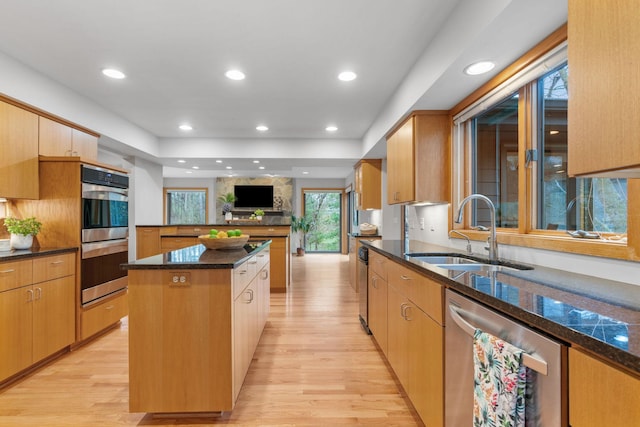 kitchen featuring a sink, a center island, stainless steel appliances, and light wood-type flooring