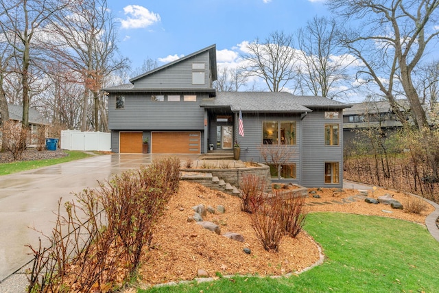 view of front of property featuring fence, roof with shingles, an attached garage, a front yard, and concrete driveway