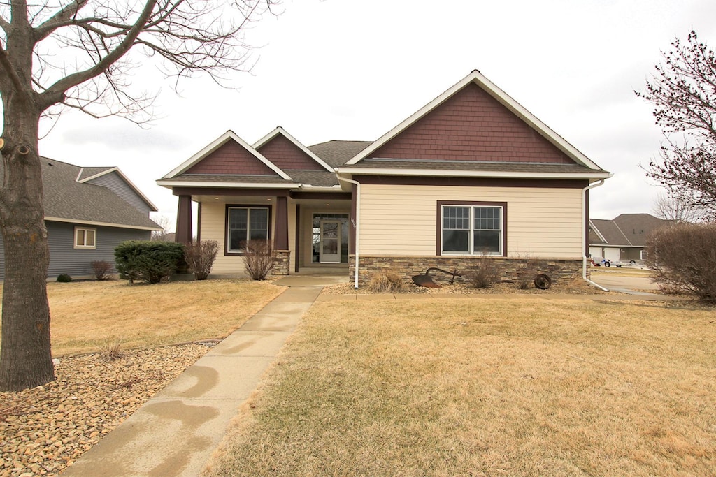 craftsman house featuring a front lawn and stone siding