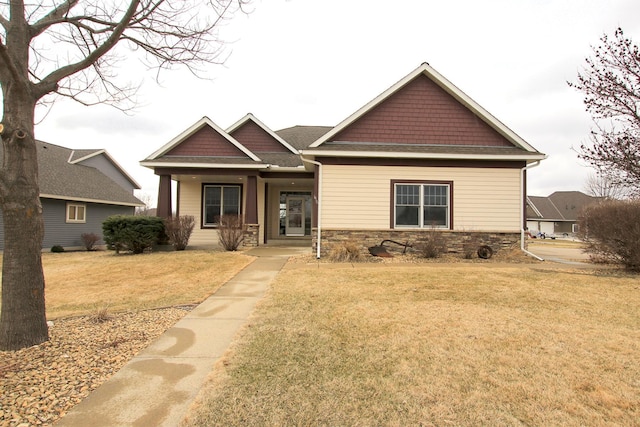 craftsman house featuring a front lawn and stone siding