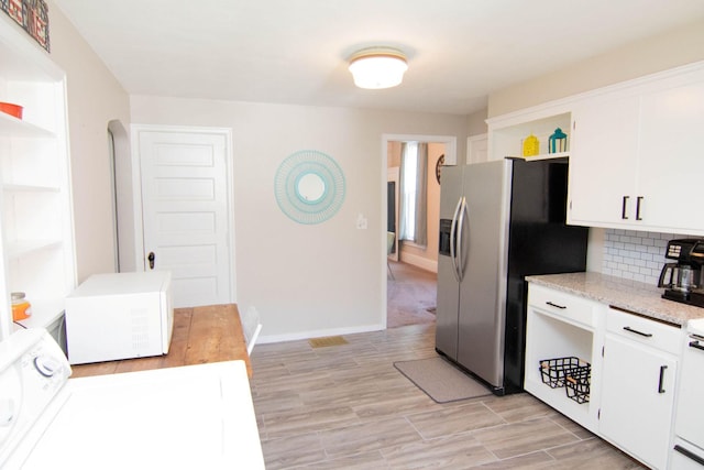 217 Center St, Mankato, MN 56001 - kitchen with stainless steel refrigerator with ice dispenser, white microwave, white cabinetry, and open shelves