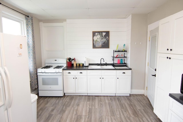 217 Center St, Mankato, MN 56001 - kitchen featuring a sink, light wood-type flooring, dark countertops, white appliances, and white cabinetry
