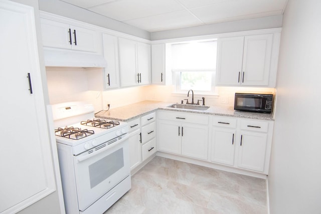 217 Center St, Mankato, MN 56001 - kitchen with white gas range oven, black microwave, white cabinets, under cabinet range hood, and a sink