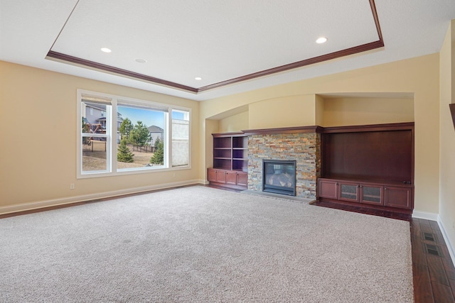 unfurnished living room with baseboards, ornamental molding, recessed lighting, a fireplace, and a tray ceiling