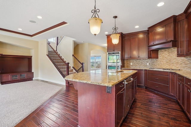 kitchen featuring light stone counters, under cabinet range hood, stainless steel appliances, arched walkways, and a sink