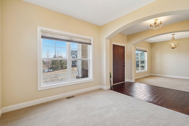 entryway featuring plenty of natural light, carpet flooring, visible vents, and an inviting chandelier