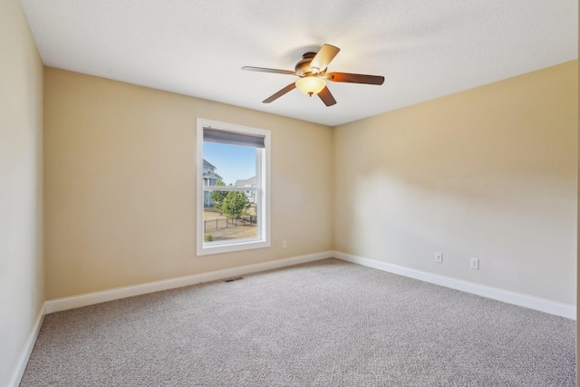 carpeted spare room with ceiling fan, baseboards, and visible vents
