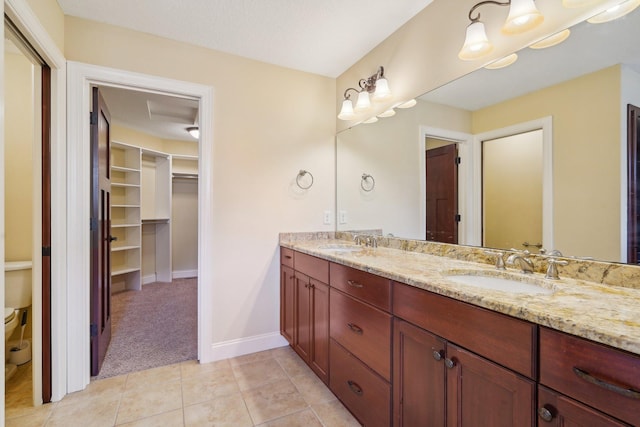 full bath with a sink, a walk in closet, double vanity, and tile patterned flooring