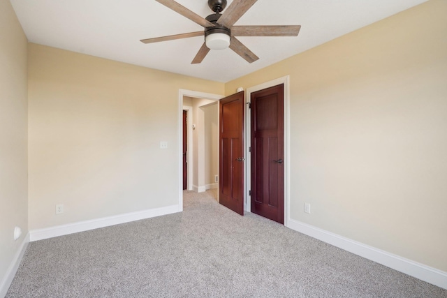 empty room featuring baseboards, a ceiling fan, and light colored carpet