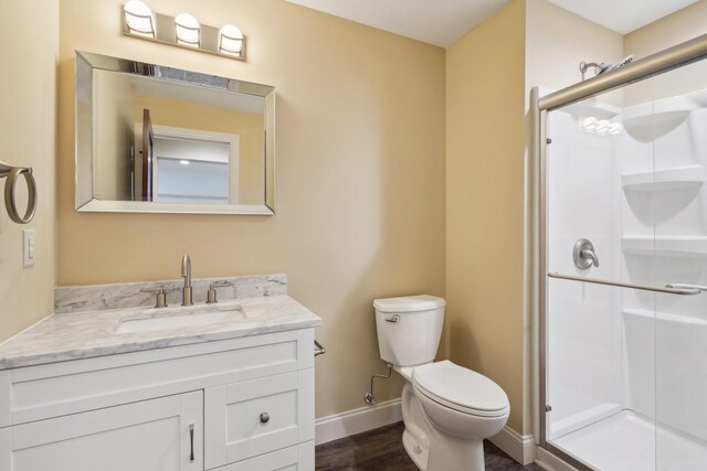 full bathroom with vanity, toilet, wood finished floors, a stall shower, and baseboards