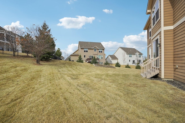 view of yard with entry steps, fence, and a residential view