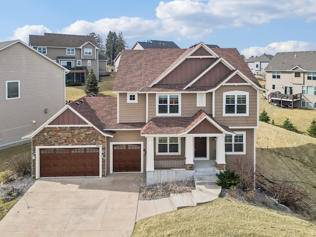 craftsman-style home featuring driveway, board and batten siding, stone siding, and a shingled roof