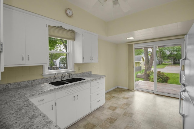 509 Nicollet Ave, North Mankato, MN 56003 - kitchen with a sink, white cabinets, decorative backsplash, freestanding refrigerator, and a ceiling fan