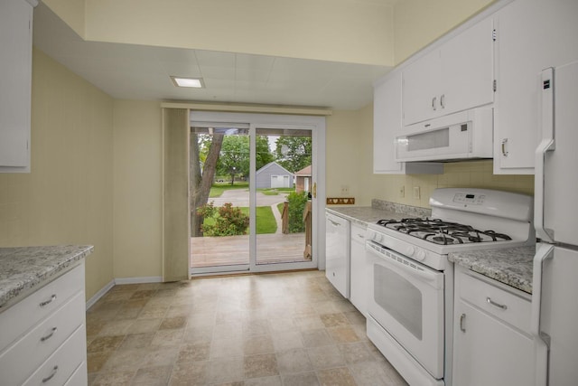 509 Nicollet Ave, North Mankato, MN 56003 - kitchen with white appliances, white cabinets, baseboards, tasteful backsplash, and stone finish flooring