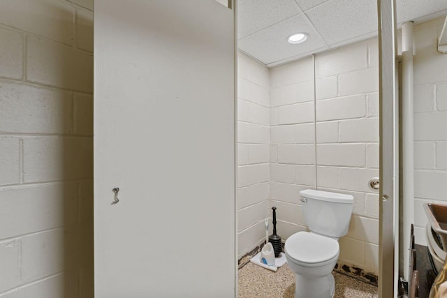 bathroom with toilet, concrete block wall, and recessed lighting