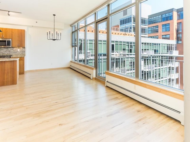 interior space featuring light wood-style floors, a baseboard heating unit, and an inviting chandelier