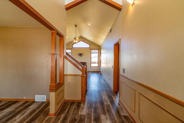 hallway with lofted ceiling, visible vents, a wainscoted wall, and dark wood finished floors
