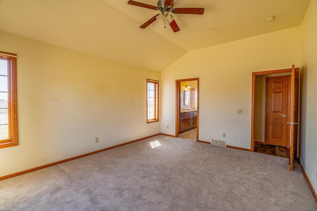 unfurnished room featuring carpet, a ceiling fan, vaulted ceiling, visible vents, and baseboards