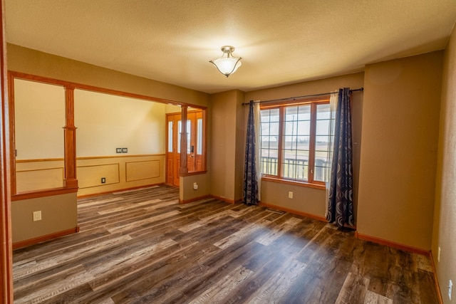 unfurnished room featuring baseboards, wood finished floors, and a textured ceiling