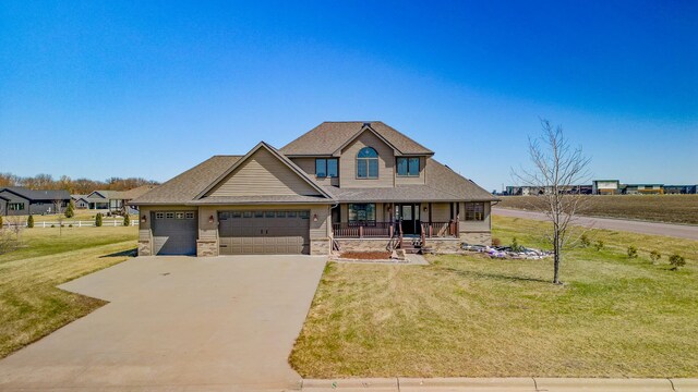 craftsman-style home with a front yard, a porch, stone siding, a garage, and driveway