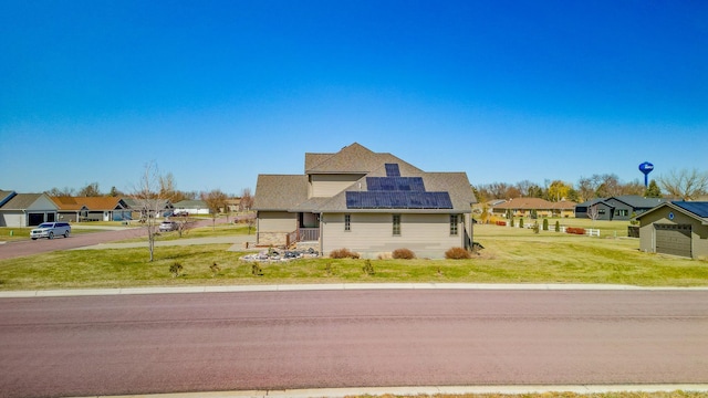 view of front of home featuring roof mounted solar panels, a front yard, and a residential view