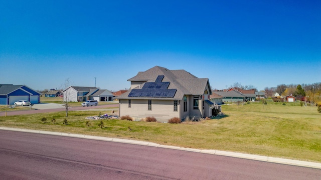 exterior space with roof mounted solar panels, a residential view, and a front lawn
