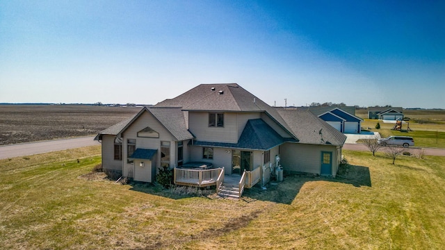 rear view of house with a yard, a shingled roof, and a deck