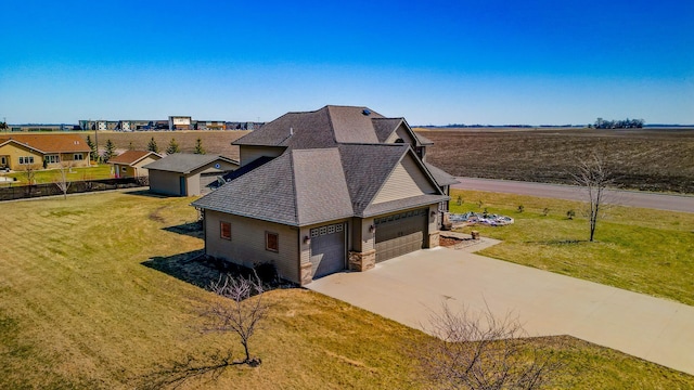 exterior space featuring roof with shingles, a yard, concrete driveway, and stone siding