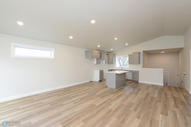 kitchen with a center island, light wood-style floors, lofted ceiling, gray cabinets, and light countertops
