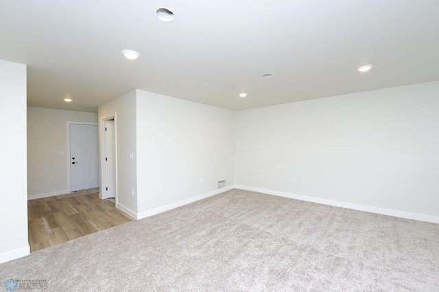 unfurnished room featuring carpet flooring, visible vents, baseboards, recessed lighting, and wood finished floors