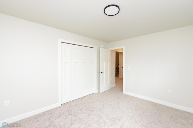unfurnished bedroom with baseboards, carpet, and a closet