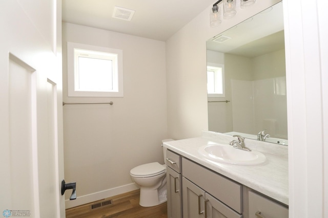 bathroom featuring wood finished floors, visible vents, toilet, and baseboards