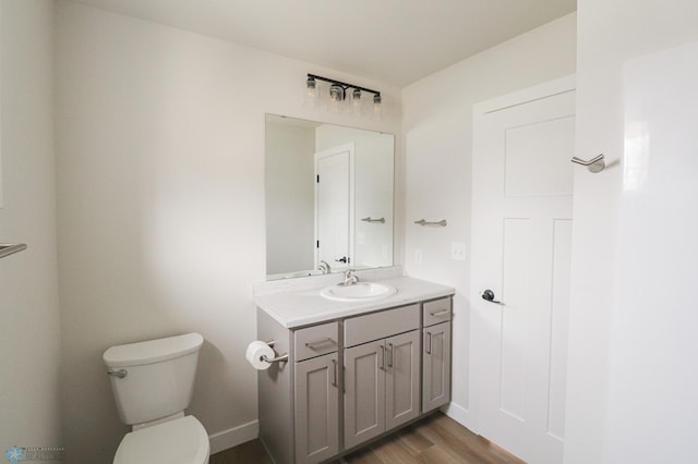 bathroom featuring toilet, vanity, wood finished floors, and baseboards