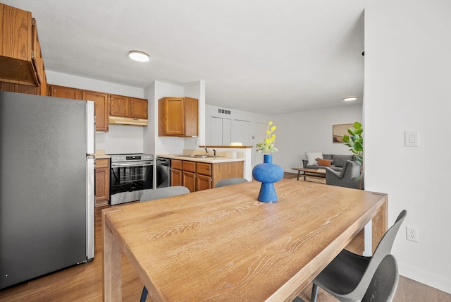 kitchen featuring appliances with stainless steel finishes, wood finished floors, a sink, and under cabinet range hood