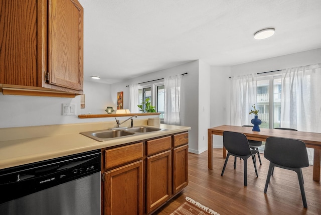 kitchen featuring light countertops, brown cabinetry, dishwasher, a sink, and wood finished floors