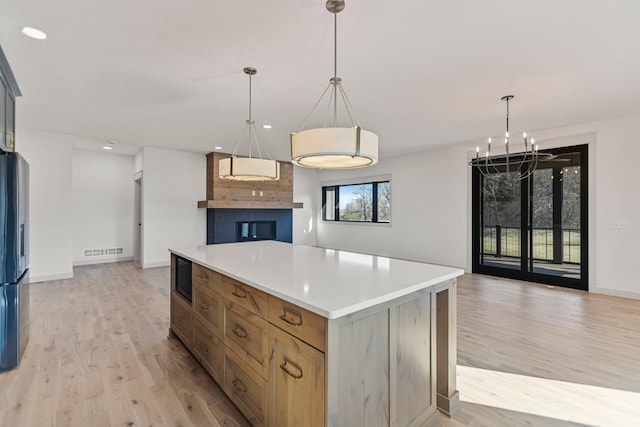 7284 205th St W, Faribault, MN 55021 - kitchen with light wood finished floors, visible vents, a kitchen island, a chandelier, and open floor plan