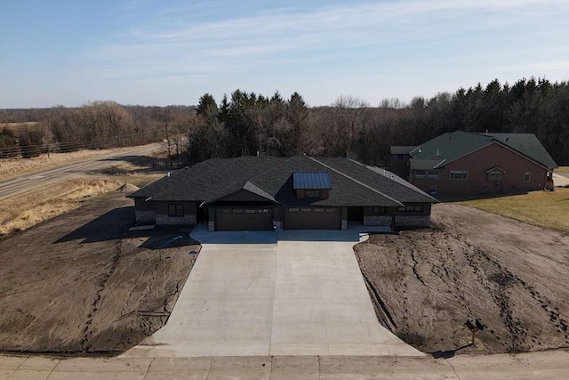 7284 205th St W, Faribault, MN 55021 - view of front of property featuring a forest view, an attached garage, a shingled roof, and concrete driveway