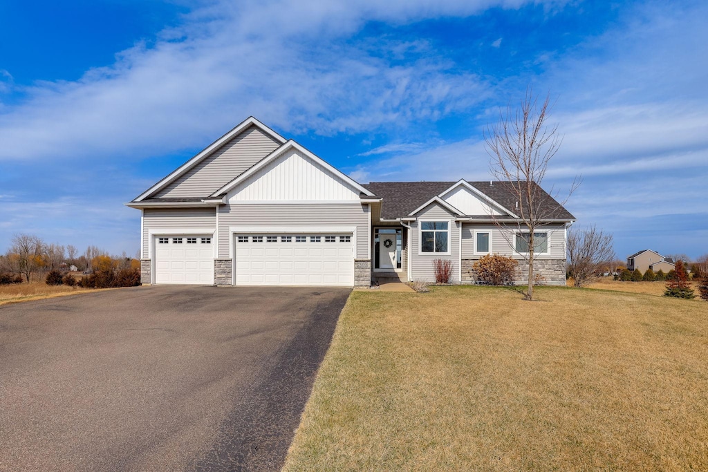 7500 244th St, Forest Lake, MN 55025 - view of front of property featuring a garage, driveway, stone siding, and a front yard