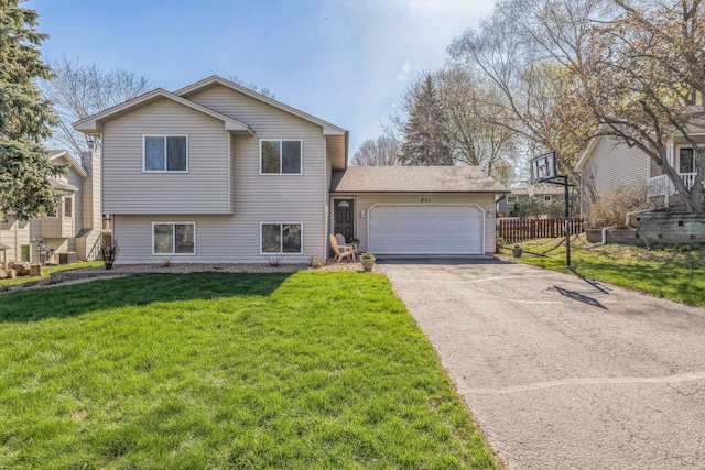 split level home with a garage, aphalt driveway, fence, and a front yard
