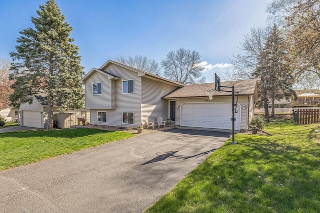 tri-level home featuring driveway, roof with shingles, fence, a front lawn, and an attached garage