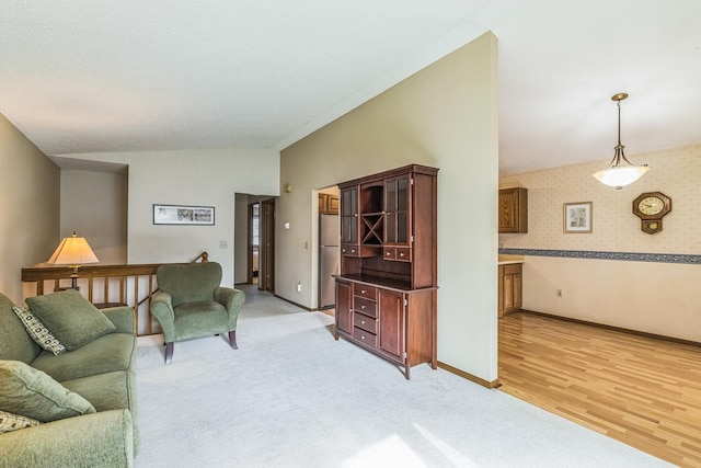 living room featuring light colored carpet, baseboards, wallpapered walls, lofted ceiling, and light wood-type flooring