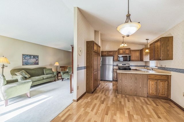 kitchen featuring open floor plan, wallpapered walls, light wood-style flooring, appliances with stainless steel finishes, and vaulted ceiling