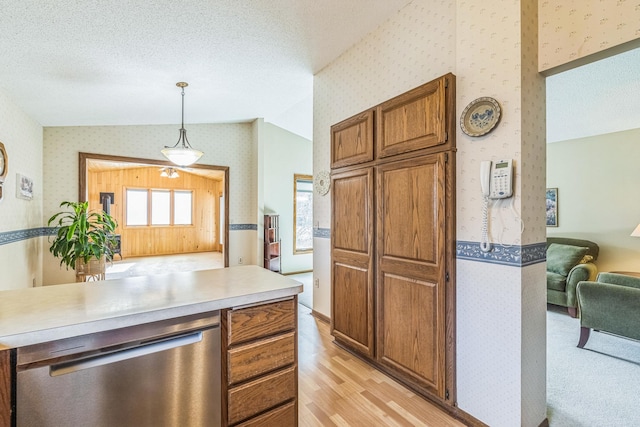 kitchen featuring brown cabinetry, dishwasher, light countertops, light wood-style floors, and wallpapered walls
