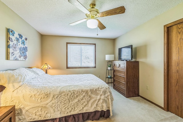 bedroom featuring light colored carpet, a ceiling fan, a textured ceiling, and baseboards
