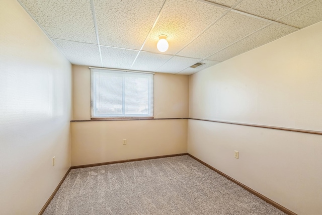 empty room featuring visible vents, carpet, a paneled ceiling, and baseboards