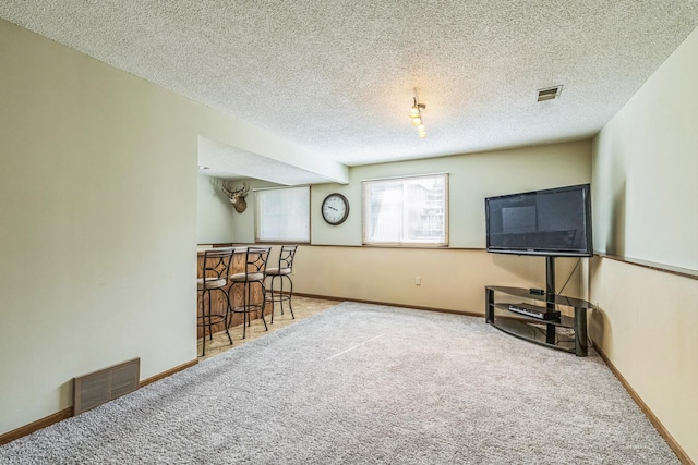 interior space featuring a textured ceiling, visible vents, a dry bar, and baseboards