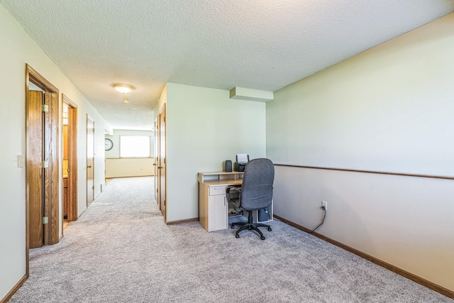 office space featuring a textured ceiling, light colored carpet, and baseboards