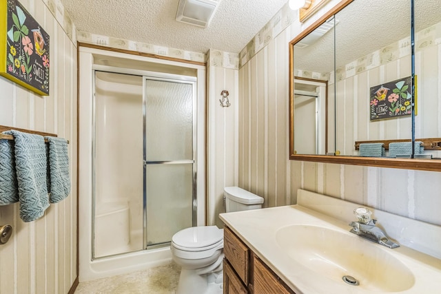 full bath featuring a stall shower, wallpapered walls, a textured ceiling, and toilet